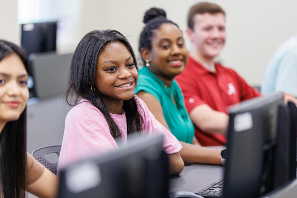 Students smiling and listening to professor in classroom